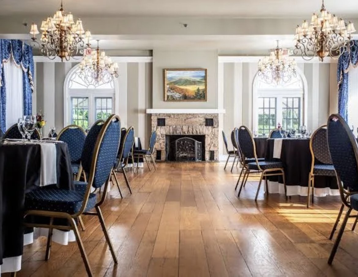 The Mimslyn's grand dining room — crystal chandeliers, a stone fireplace and dressed tables on wide oak floors