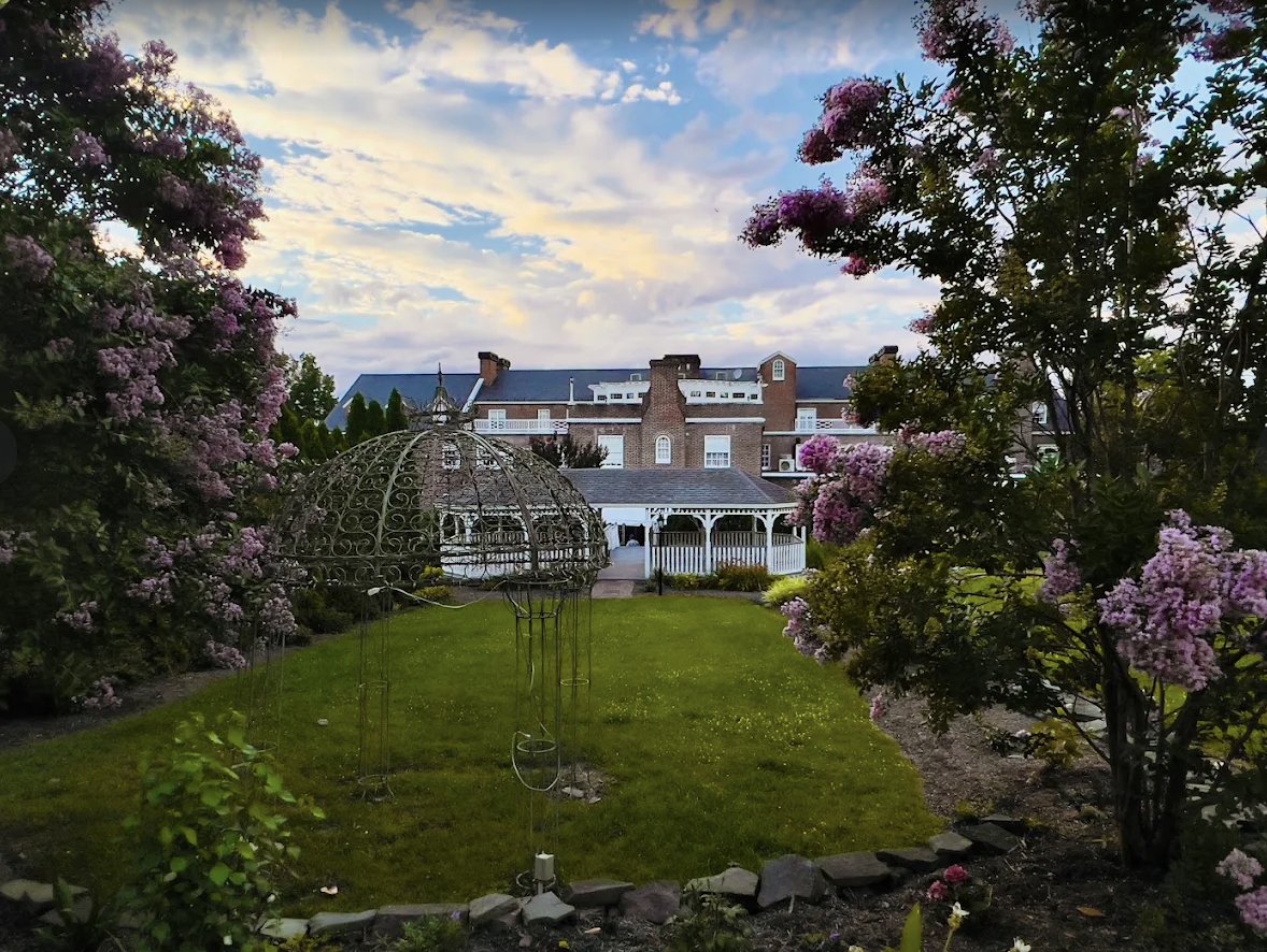 The Mimslyn Inn's gardens at golden hour — iron gazebo, blooming crepe myrtles and the inn beyond